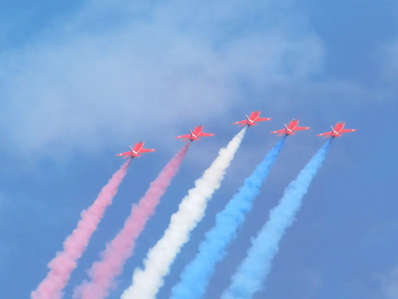 In this image I can see five aircrafts. I can also see smoke in red, white and blue color....