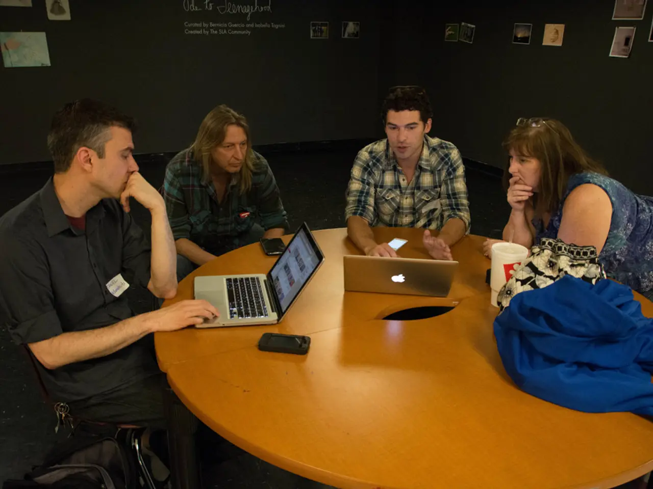 in this image there are four people who are working on a laptop. To the left side there is a man...