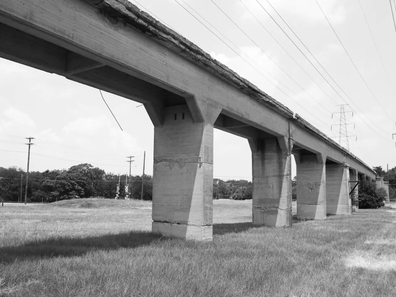 In this picture there is a concrete bridge on the green lawn and above we can see huge electric...