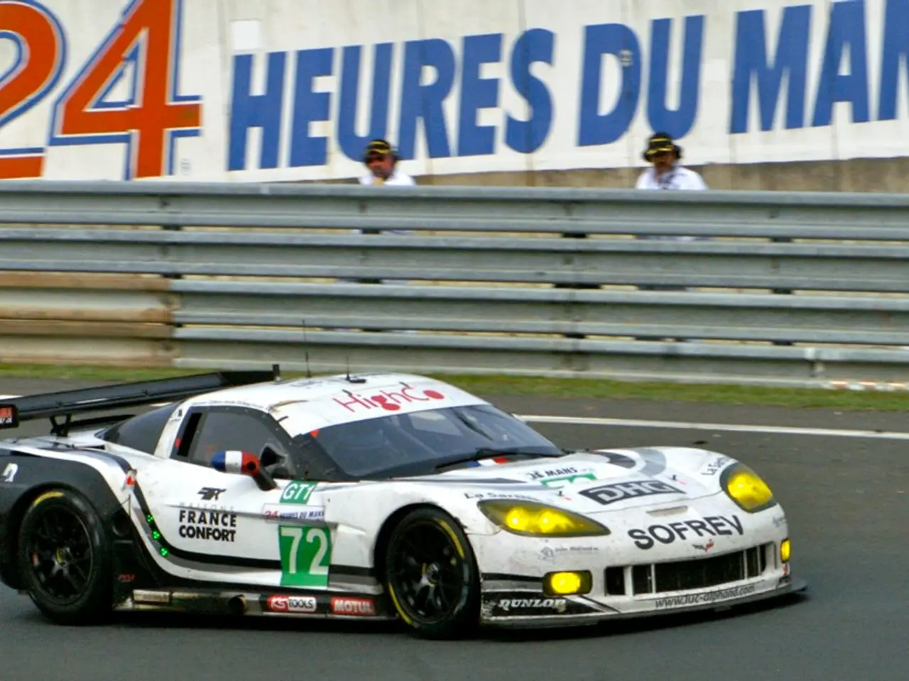 In this image I can see a sports car in white color on the road, in the middle there are iron...