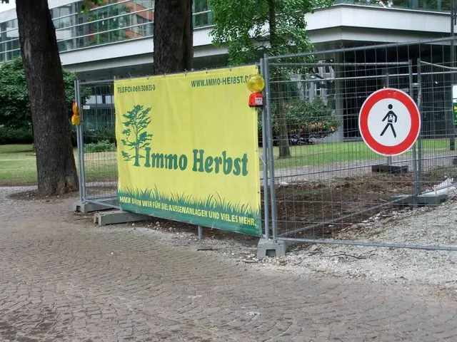 In this image there is a fence having few boards and a banner are attached to it. Left side there...