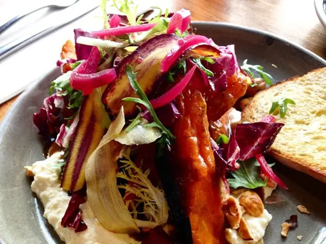 On this wooden surface there is a plate with food and knife.