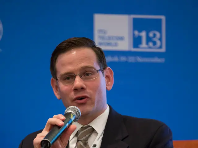 A man is sitting on the chair and he is talking on the microphone.