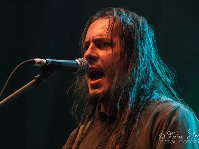 In this picture we can see a person in front of a microphone. There is a watermark and some text is...