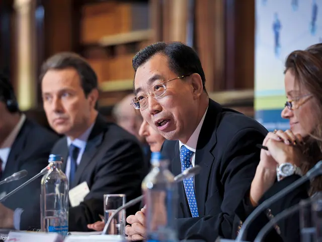 As we can see in the image, there are few people sitting and the man who is sitting here is talking...