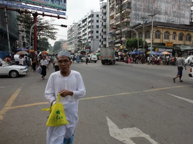 a person is walking, holding a yellow bag in his hand on the road. at the right and left there are...
