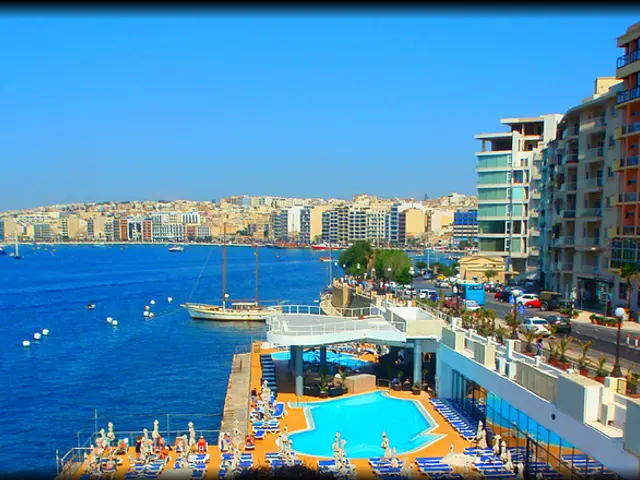 There are some boats and ships on the sea in the middle of this image, and there are some buildings...